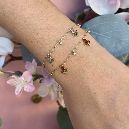 Bracciale Rugiada dorato in acciaio inox con charm floreali rosa, foglie verdi e piccoli cristalli luminosi