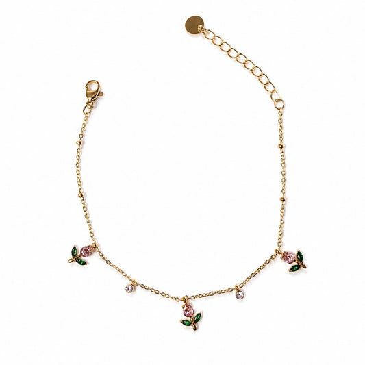 Bracciale Rugiada dorato in acciaio inox con charm floreali rosa, foglie verdi e piccoli cristalli luminosi