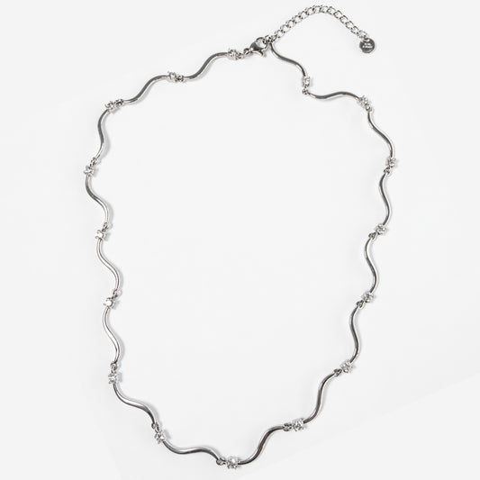 Collana Elettra in acciaio inox con design ondulato e punti luce su sfondo chiaro
